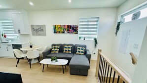 A modern living room with a grey sofa, white chairs, a small round table, and a white coffee table. - Fully AC 2 Bed 2 Bath Apartment (Surrey)