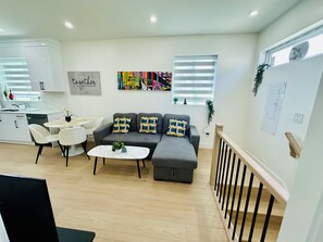 A modern living room with a grey sofa, white chairs, a small round table, and a white coffee table. - Fully AC 2 Bed 2 Bath Apartment (Surrey)