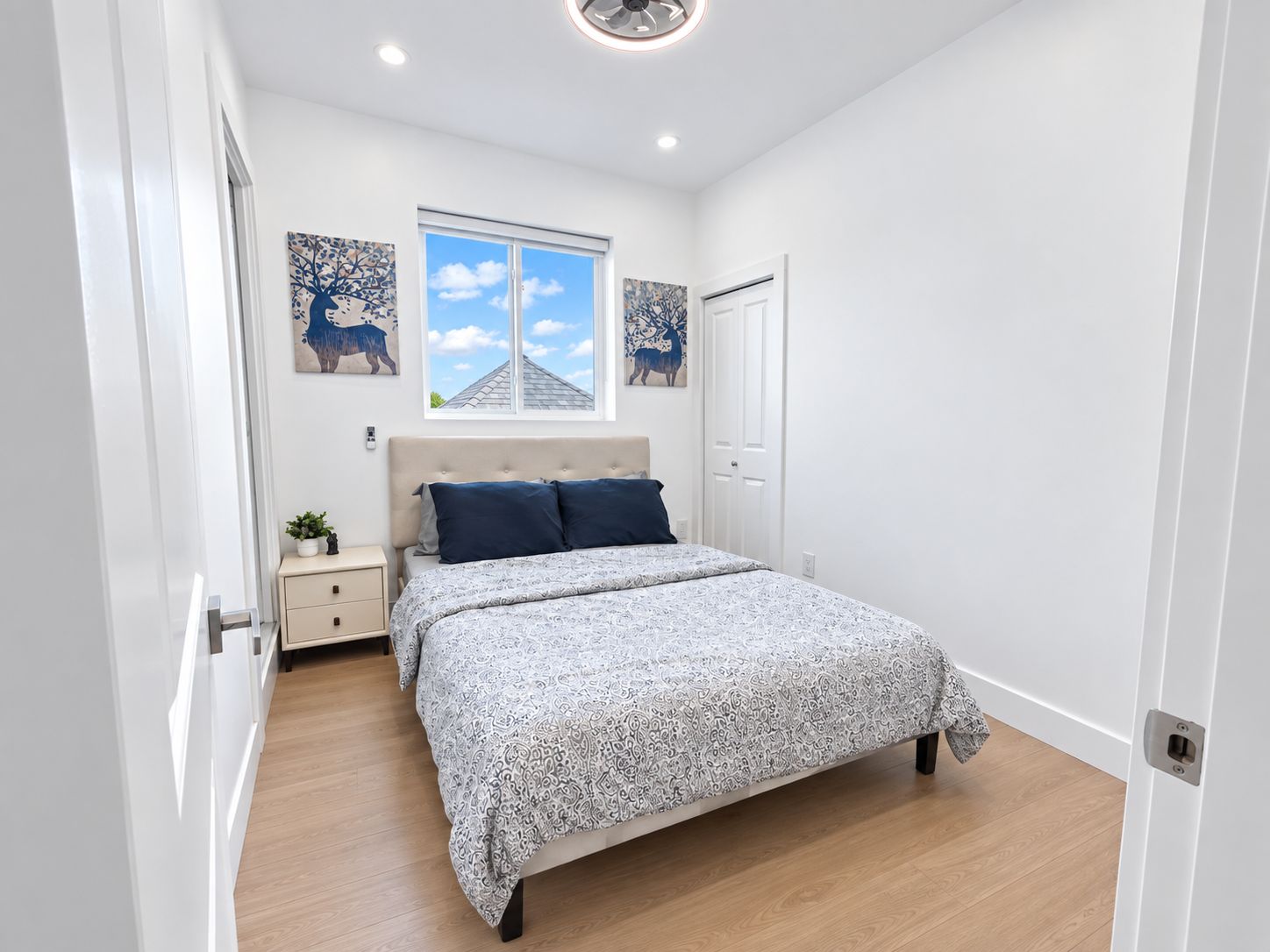 Un dormitorio con cama, mesita de noche, ventana y decoración en la pared.