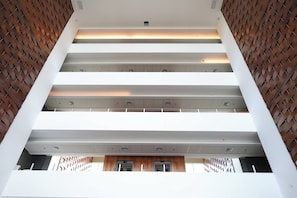 A multi-level interior with a central open space, white structural elements, and a patterned wall on the sides.