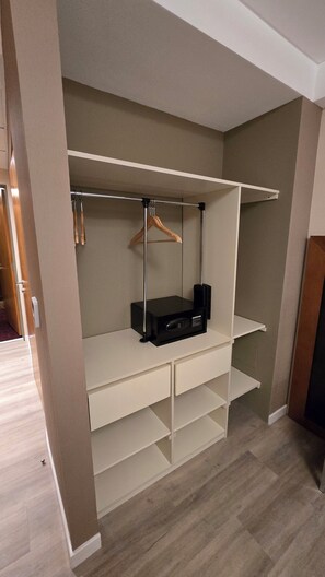 A walk-in closet with open shelving, a hanging rod, and a black electronic device on the middle shelf. - Azahar Hotel & Spa (San Pedro)