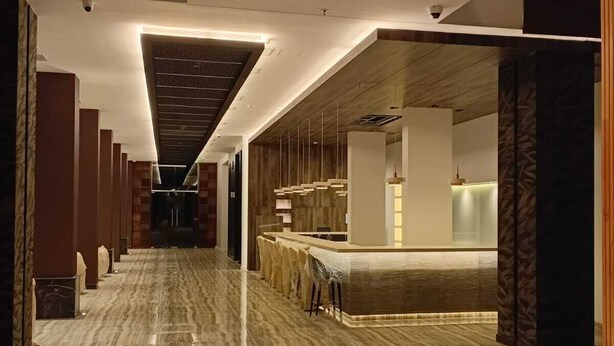 Un moderno vestíbulo de hotel con piso de mármol, un mostrador de recepción y un largo pasillo con detalles de madera.