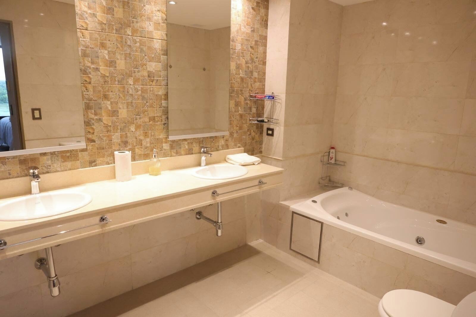 A bathroom with two sinks, a bathtub, and a large mirror.