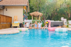 A swimming pool with inflatable toys and a thatched-roof structure. - Pool, Hot Tub, PickleBall, Firepit, 5 min to IMG (Bradenton)