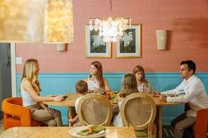 A family dining at a table with a decorative wall and framed pictures above. - Pool, Hot Tub, PickleBall, Firepit, 5 min to IMG (Bradenton)
