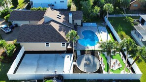 Ein Wohnhaus mit Swimmingpool, überdachter Terrasse und umzäunter Garten.