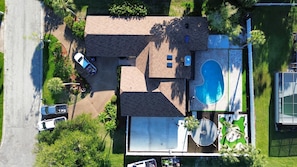 Eine Vogelperspektive auf ein Wohnanwesen mit Schwimmbad, Garage und Tennisplatz.