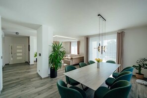 Ein modernes Wohnzimmer mit Essbereich, einer großen Pflanze und einer Deckenleuchte.