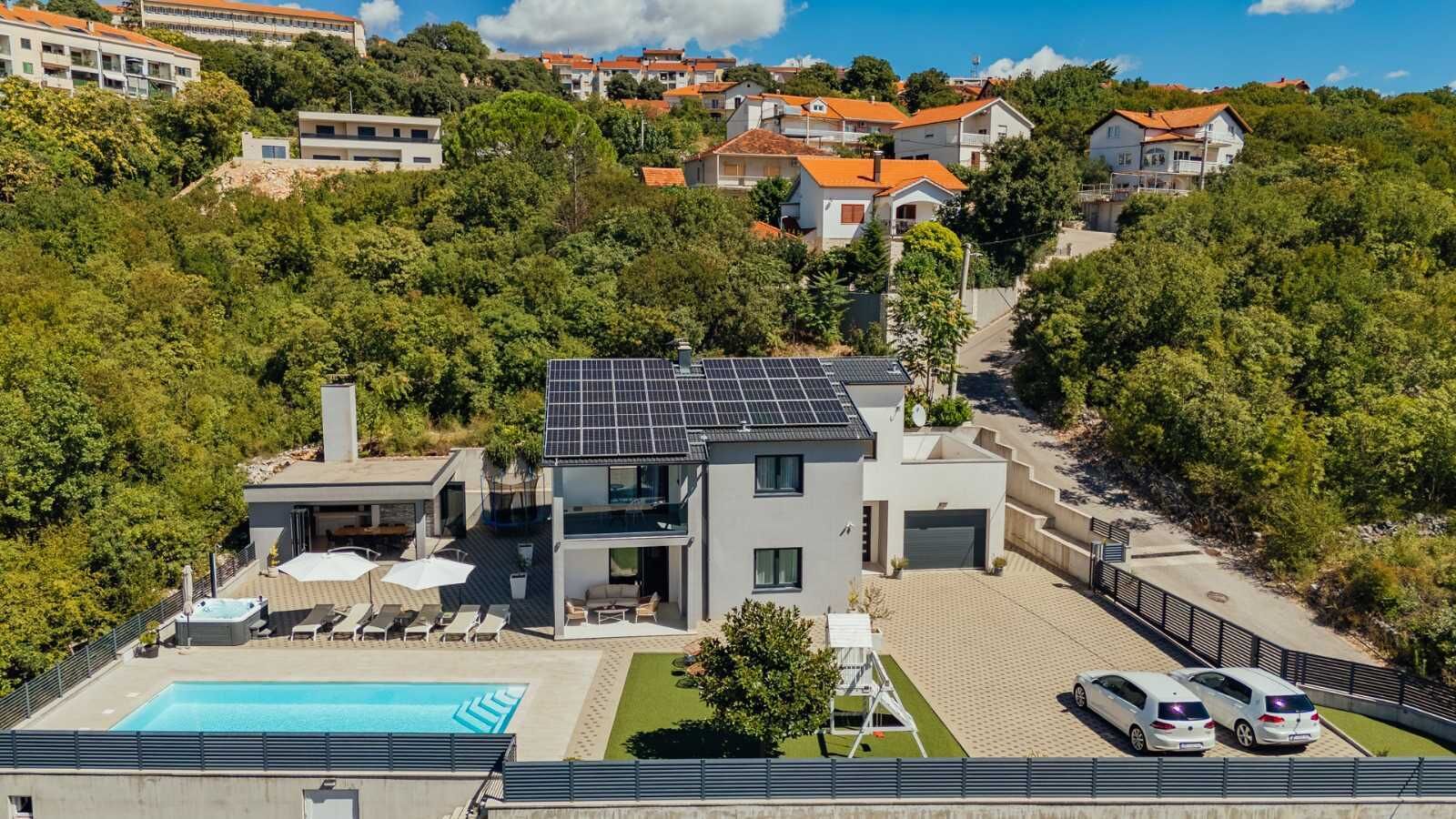 A modern two-story house with a swimming pool, solar panels, and a garage.