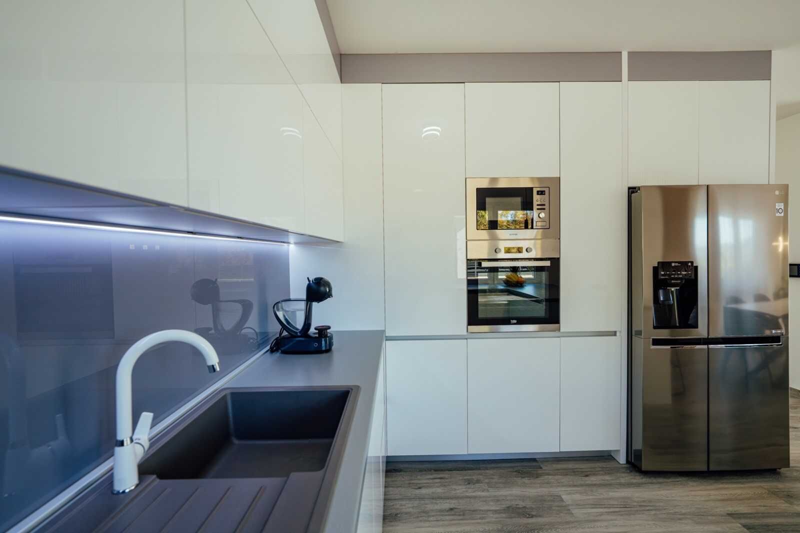 Una cocina moderna con un refrigerador de acero inoxidable, horno empotrado y una encimera elegante.