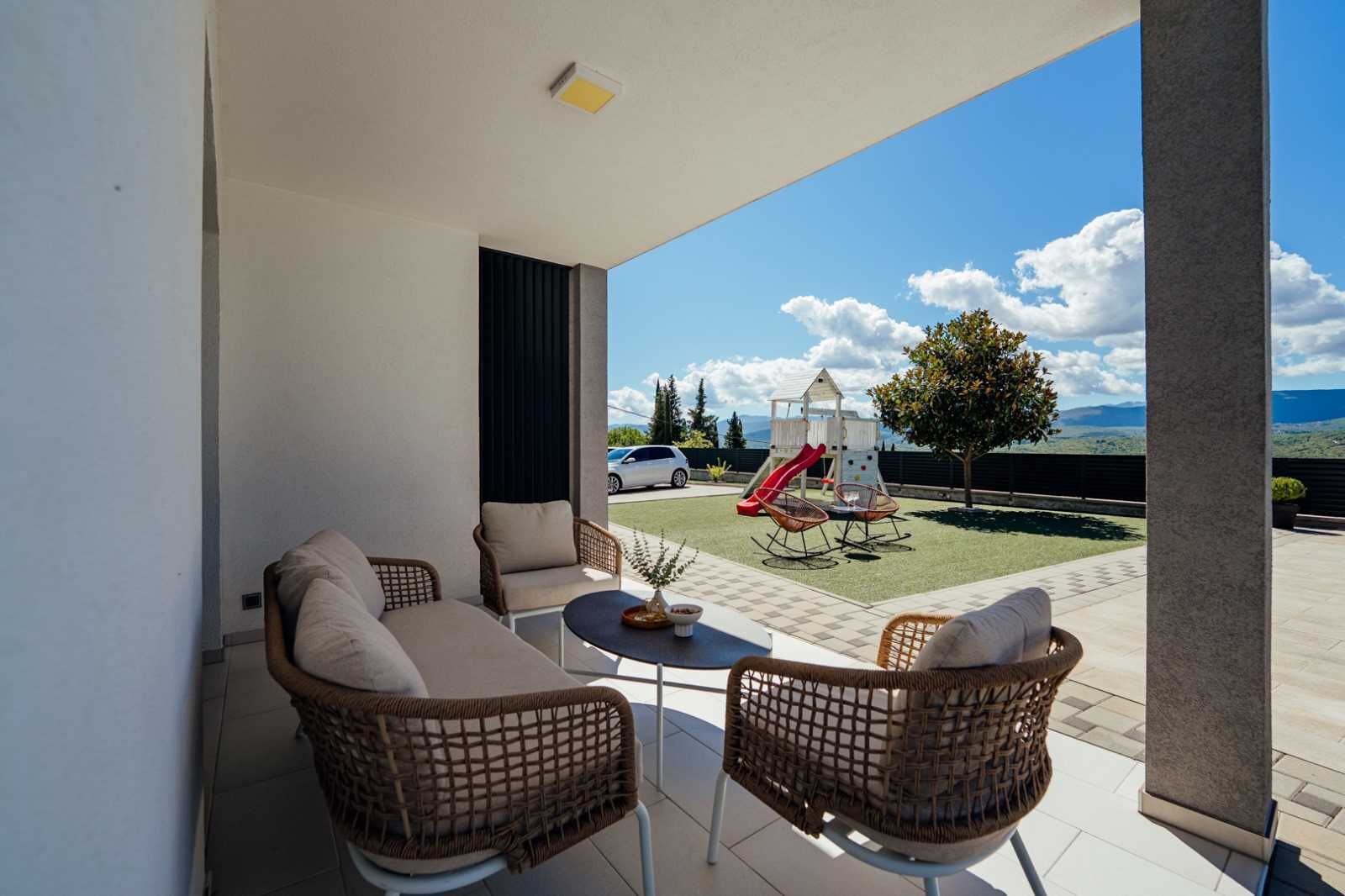 A balcony with wicker furniture, a small table, and a children's play structure.