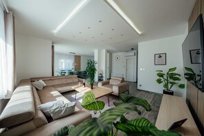 Ein modernes Wohnzimmer mit einem Ecksofa, einem Couchtisch und Topfpflanzen.