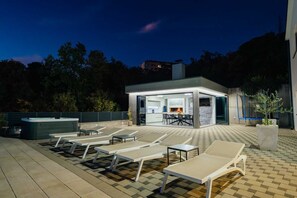 Eine Außenpatio mit Lounge-Möbeln, einem Whirlpool und einem Essbereich mit Kamin.