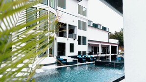 Un edificio moderno con piscina, zona de estar al aire libre y balcón.