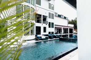 A modern building with a pool, outdoor seating, and a balcony. - Gated Luxury Retreat, 15 Min from ATL Airport, Modern Amenities, Sleep up to 20P (Fairburn)