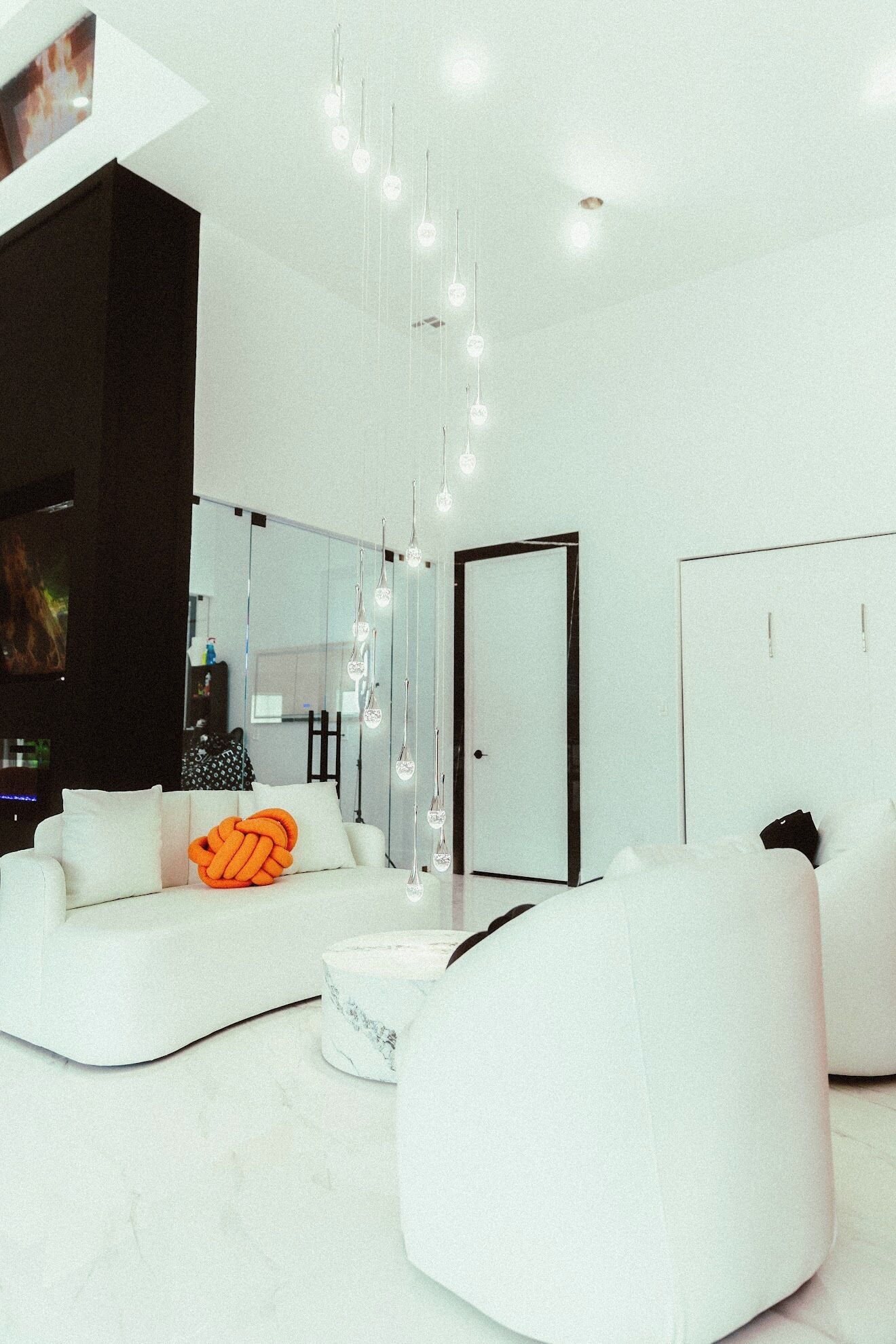 Una sala de estar moderna con sofás blancos, una mesa de centro y lámparas colgantes.