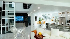Un interior moderno con un separador de vidrio, un sofá blanco, una zona de comedor y una cocina.