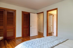 Ein Schlafzimmer mit einem Bett, Holztüren und einem Flur.