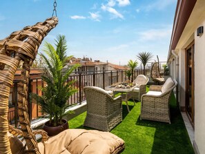 A balcony with wicker furniture, a table with dishes, and potted plants. - Huge Balcony Taksim Rooftop Apt At Monnas Suite (Istanbul)