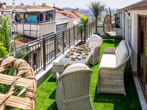 A rooftop terrace with wicker furniture, a dining table with food, and a view of the cityscape. - Huge Balcony Taksim Rooftop Apt At Monnas Suite (Istanbul)