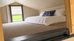 Un dormitorio con cama, ventana y cabecera de madera.