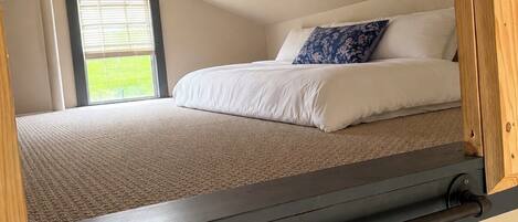 Un dormitorio con cama, ventana y cabecera de madera.