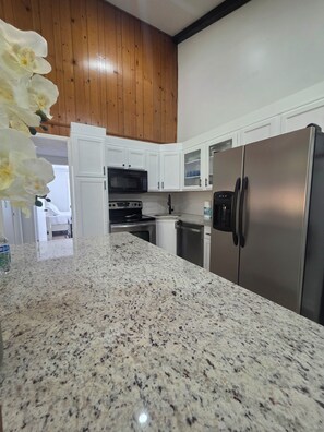 A kitchen with granite countertops, stainless steel appliances, white cabinets, and wooden ceiling. - Lake Lanier Getaway. Hot Tub & Fire Pit. 5-Min Walk to Lake Access (Flowery Branch)