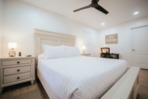 A bedroom with a bed, nightstands, a ceiling fan, and a wall sign. - Lake Lanier Getaway. Hot Tub & Fire Pit. 5-Min Walk to Lake Access (Flowery Branch)
