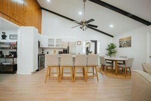 A modern kitchen with white cabinets, a dining area with four chairs, and a ceiling fan. - Lake Lanier Getaway. Hot Tub & Fire Pit. 5-Min Walk to Lake Access (Flowery Branch)