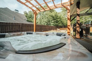 A hot tub under a wooden pergola with a wooden fence and trees in the background. - Lake Lanier Getaway. Hot Tub & Fire Pit. 5-Min Walk to Lake Access (Flowery Branch)