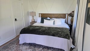 Ein Hotelzimmer mit Bett, Nachttisch, Lampe und einem gemusterten Teppich.