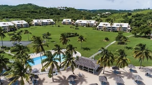 Ein Resort mit mehreren Gebäuden, einem Pool, Palmen und einem Strandabschnitt.