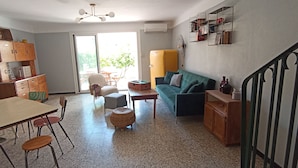 Een woonkamer met een eethoek, een bank, een tafel en een ventilator.
