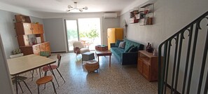 Ein Wohnzimmer mit Essbereich, einer Couch, einem Tisch und einem Ventilator.