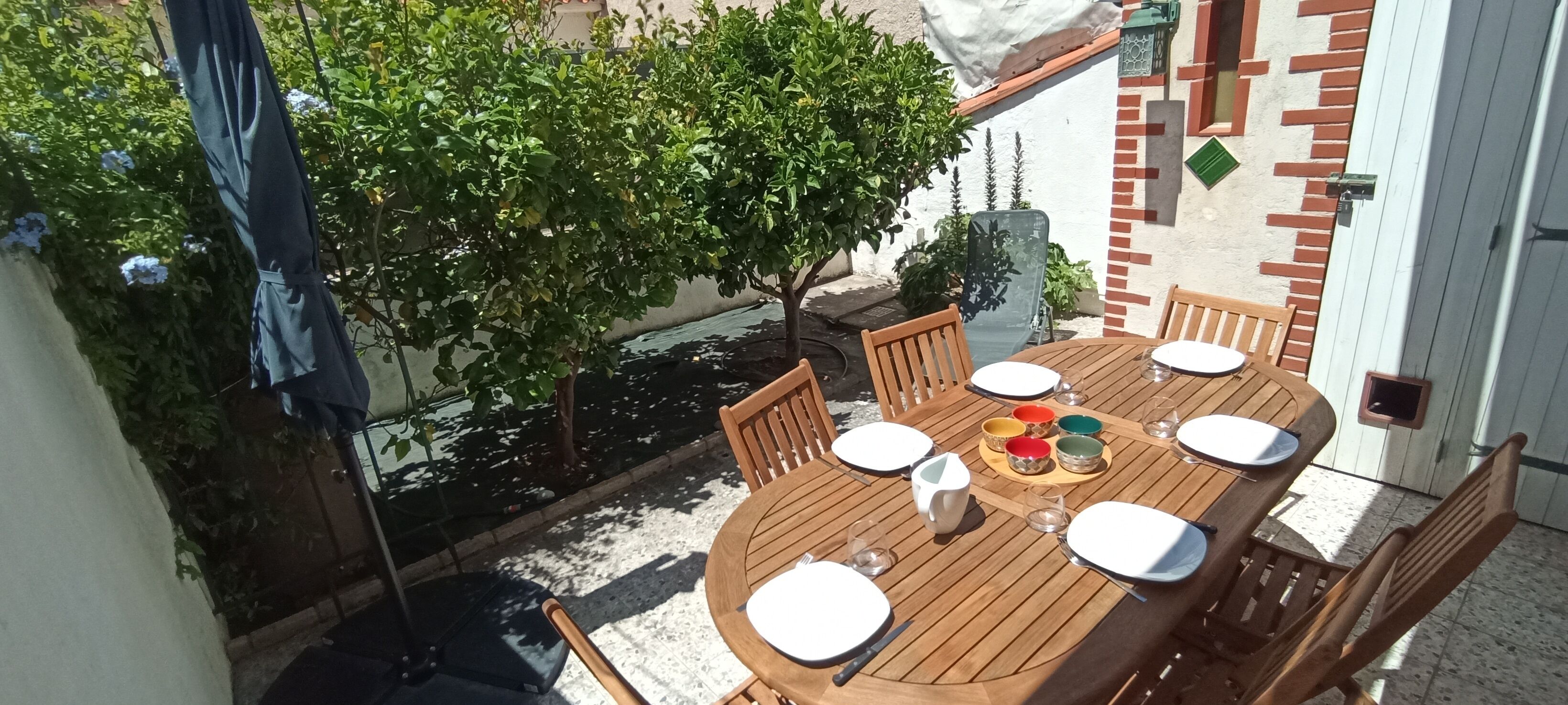 A wooden dining table set for four with plates, bowls, and cutlery.