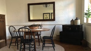 Un comedor con una mesa redonda, cuatro sillas, un espejo y una planta en maceta.