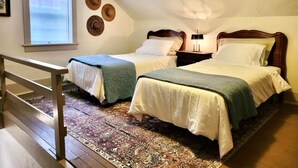 Un dormitorio con dos camas, una ventana y una barandilla de madera.