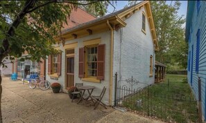 Une maison de plain-pied avec un porche, une petite table et des chaises, et un vélo.