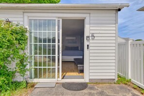 Ein kleiner, einräumiger Wohnwagen mit Glastür und Schiebetür, einem Bett und einer kleinen Sitzbank.