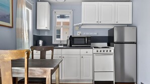 A kitchen with white cabinets, a stainless steel refrigerator, a microwave, and a stove.