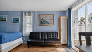 A room with a bed, a sofa, a painting, and a window.