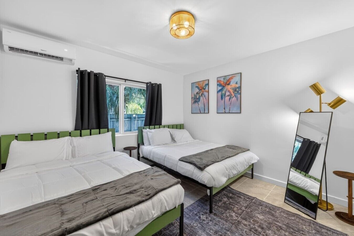 Une chambre d’hôtel avec deux lits, un grand miroir et des œuvres d’art accrochées au mur.