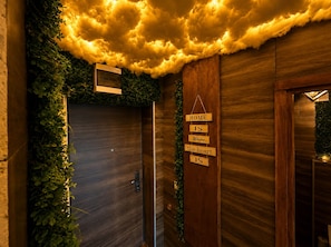 Una pared de madera con un techo que evoca nubes, un letrero que dice 'HOME IS Where the heart IS' y una puerta con un ventanal pequeño.