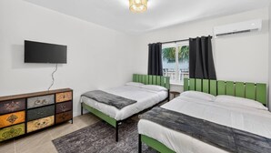 Ein Zimmer mit zwei Betten, einem Fernseher, einem Schminktisch und einer Klimaanlage.