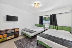 Ein Zimmer mit zwei Betten, einem Fernseher, einem Schminktisch und einer Klimaanlage.