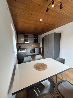 Eine moderne Küche mit Holzboden, Edelstahlgeräten und grauen Schränken.