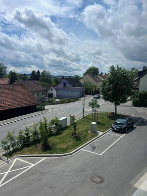 A residential street with houses, a car parked in a parking space, and a clear sky.