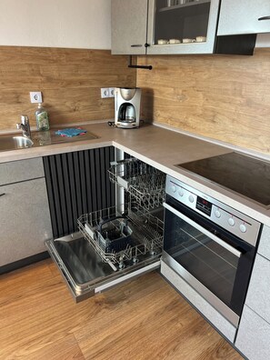 A compact kitchen with a built-in dishwasher, a coffee maker, and a stove.