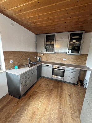 Eine moderne Küche mit Holzboden, Edelstahlgeräten und eingebauten Schränken.