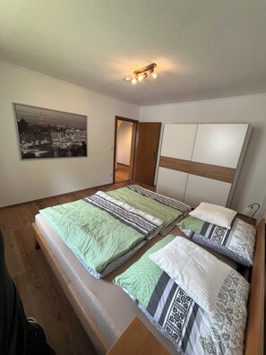 Ein Schlafzimmer mit einem Bett, einem hölzernen Kopfstück, einem Nachttisch, einer Lampe und einem Stadtbild an der Wand.
